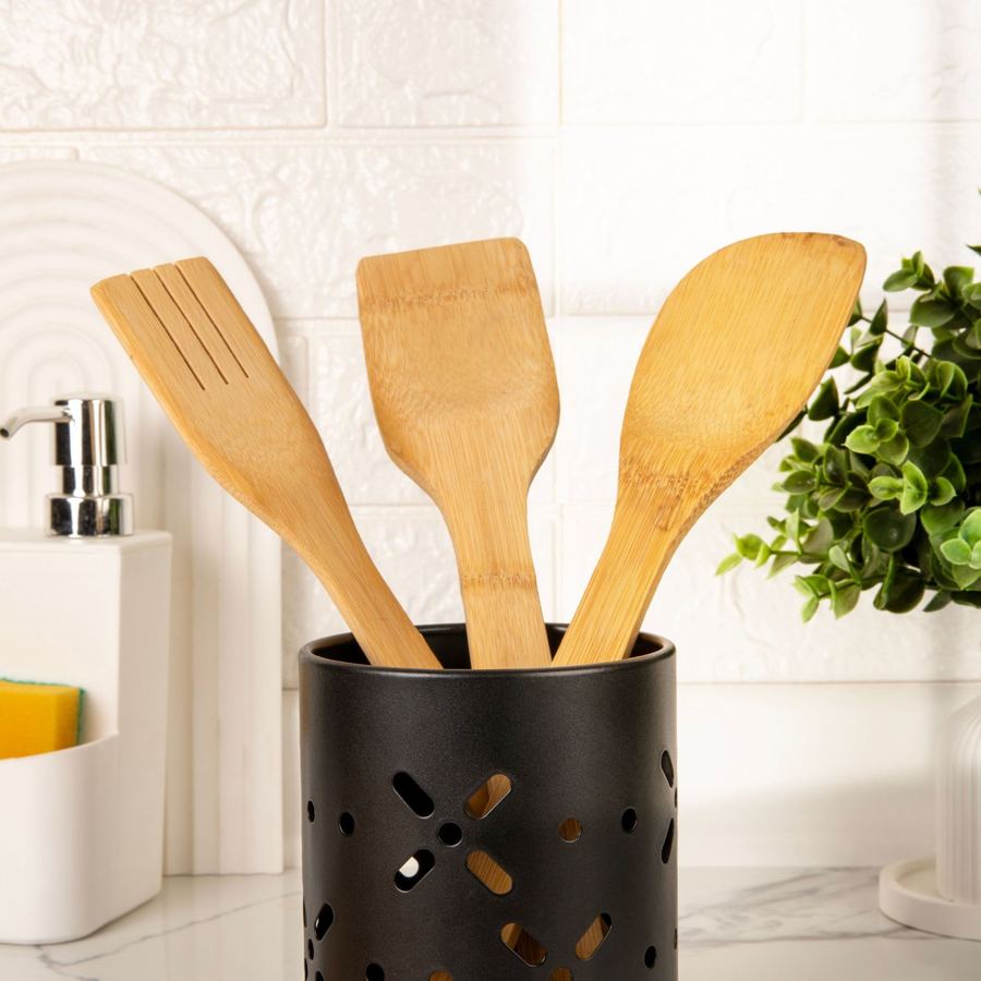 Utensilios de madera en un bote negro, con luz de ventana